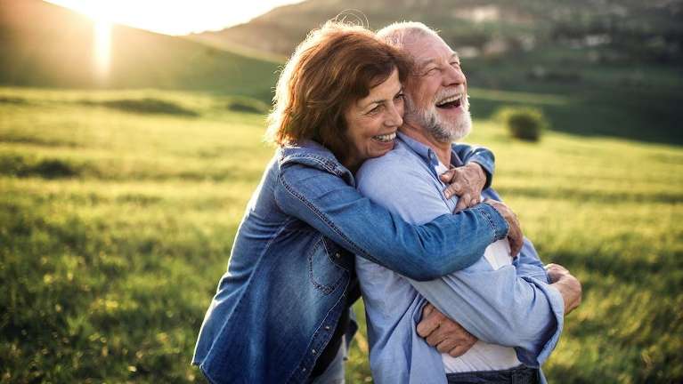 woman hugging her husband's shoulders from behind
