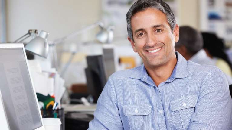 man smiling next to a computer